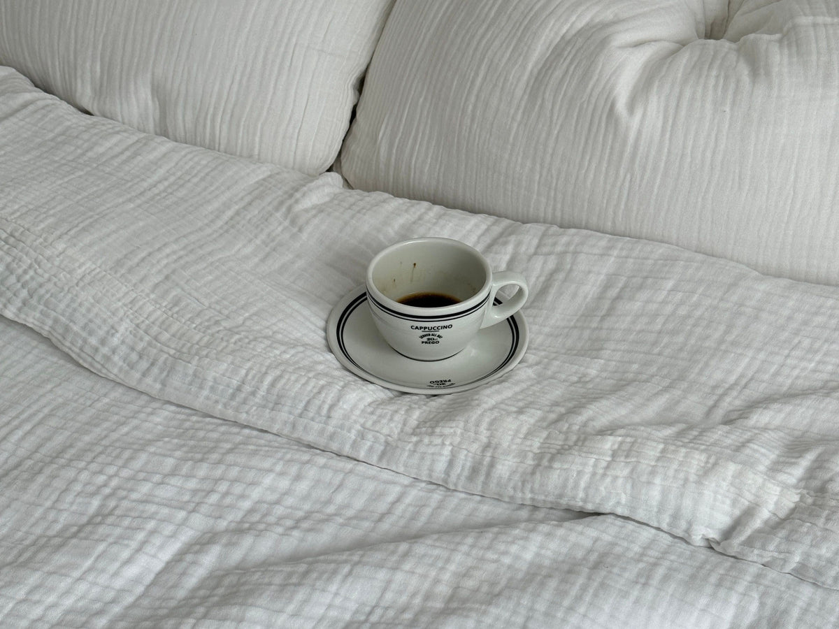 Coffee cup on white bedsheets